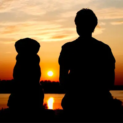 Hund mit Frauchen im Sonnenuntergang.